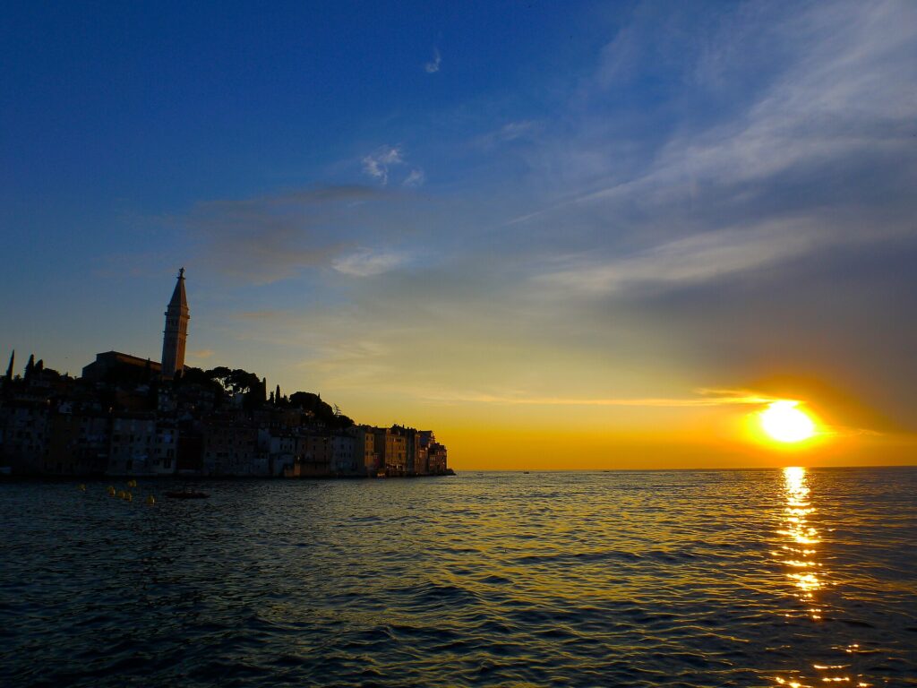 Silhouetted rooftops of Rovinj Old Town against a colourful sunset sky
