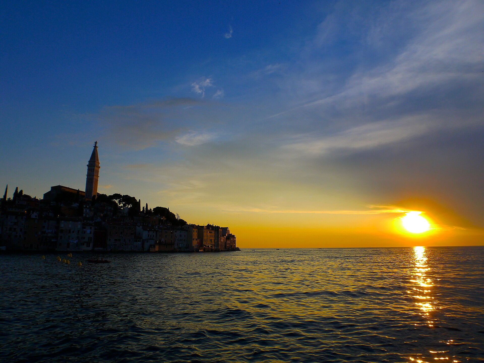 Silhouetted rooftops of Rovinj Old Town against a colourful sunset sky